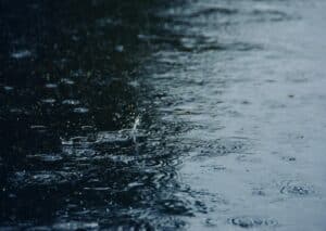 Raindrops splashing into flooded pavement